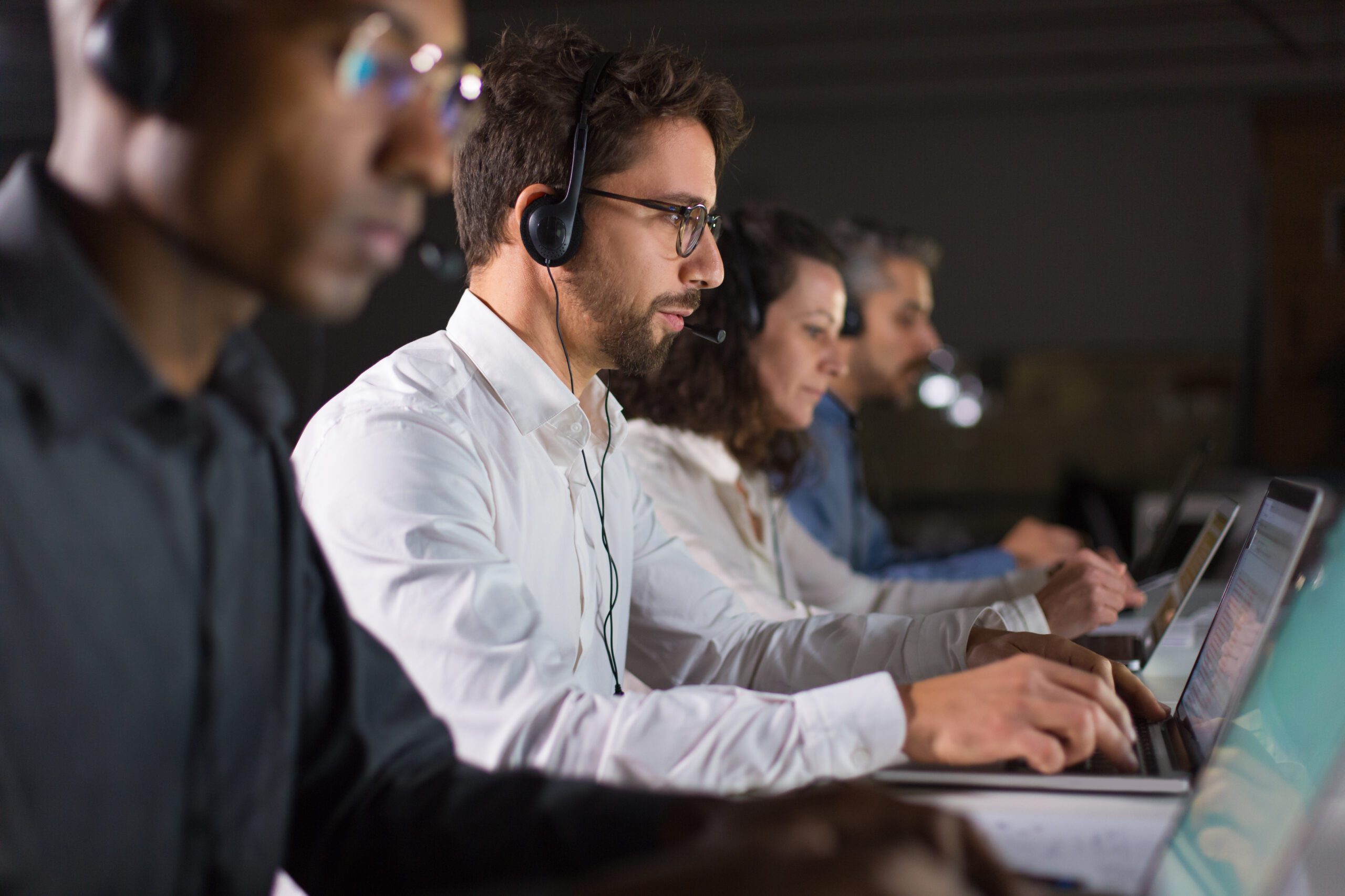 Side view of confident call center operator talking with client